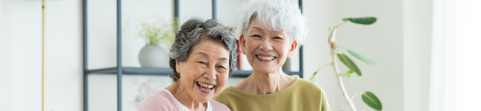 ソファに並んで座り、タブレットを見て笑う2人の高齢の女性