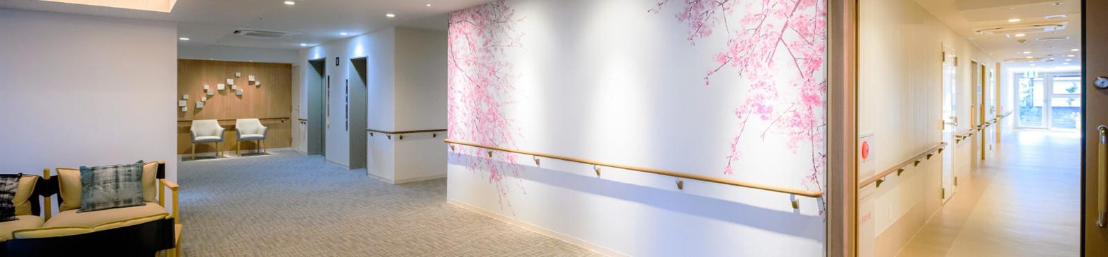 東急ウェリナケア旗の台の、桜の壁画と手すりのある居住フロアの廊下