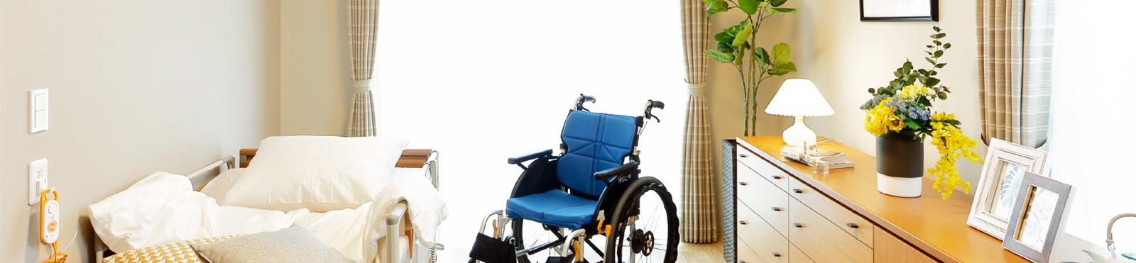 東急ウェリナケア自由が丘の居室。介護用ベッドと車いす、チェストを配置