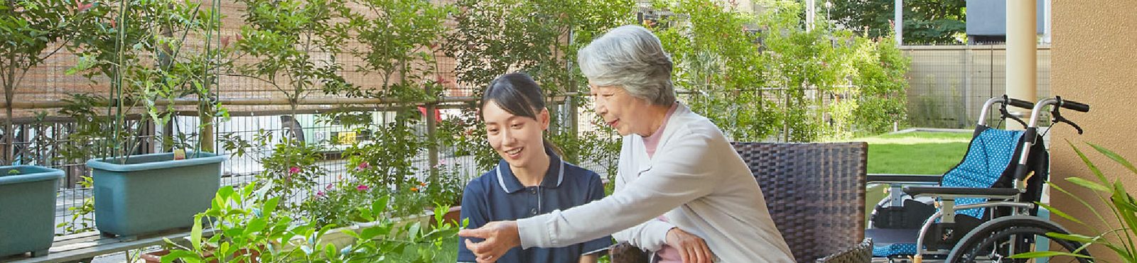 テラスで、入居者とスタッフが植物を見ながら話すようす