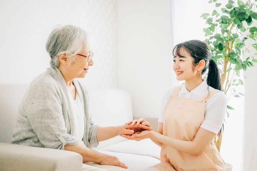 高齢の女性の手を取って話す、訪問介護のスタッフ