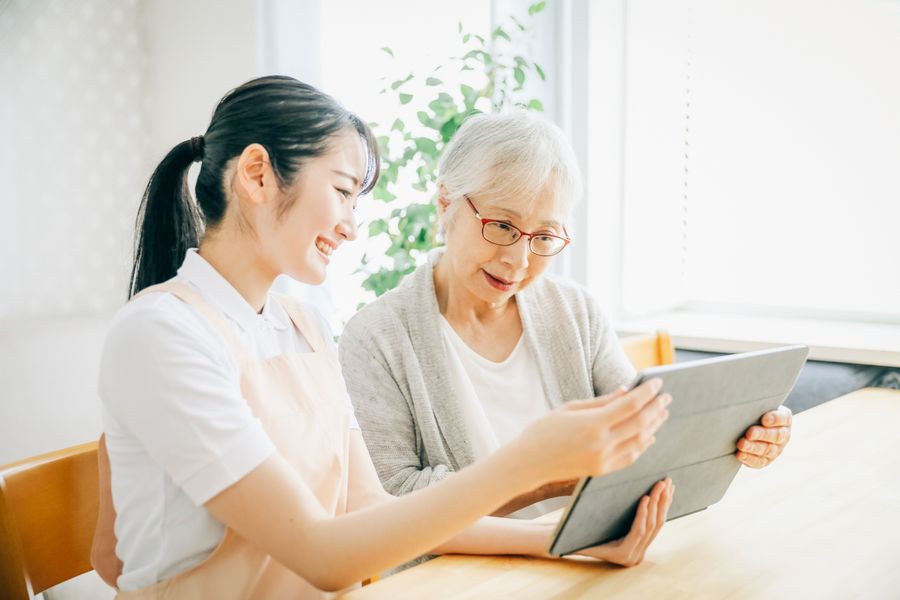 タブレットの画面を見ながら、高齢の女性と話すスタッフ