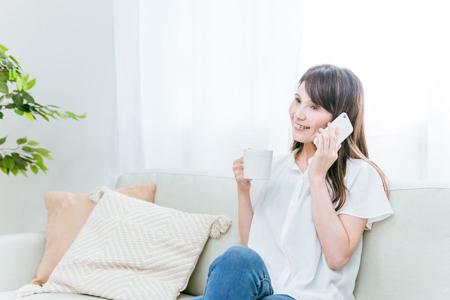 ソファに座って、電話で話す女性