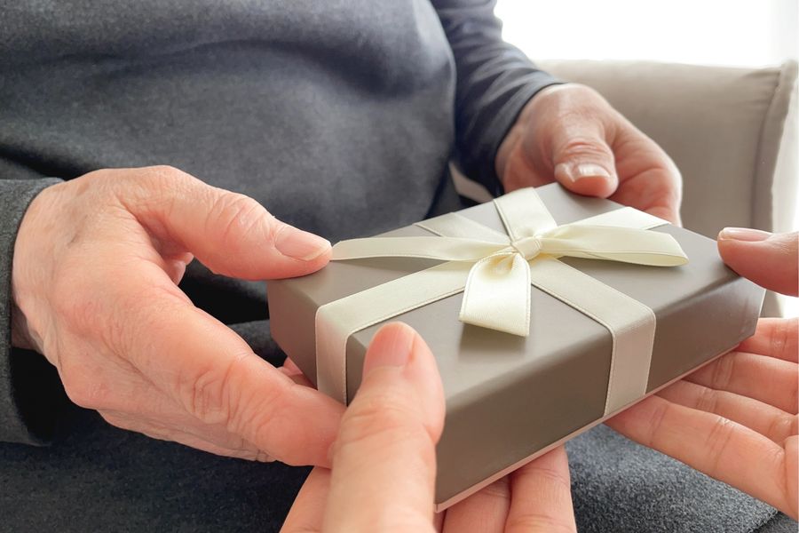 プレゼントの箱を、高齢の女性の手に手渡す