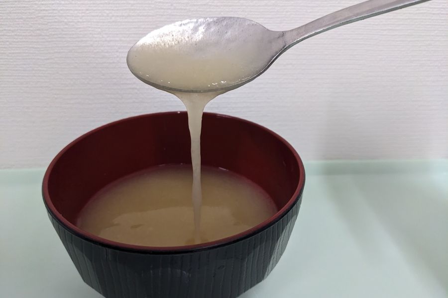 中間のとろみをつけたみそ汁を、スプーンですくって流すようす。とろとろと流れる