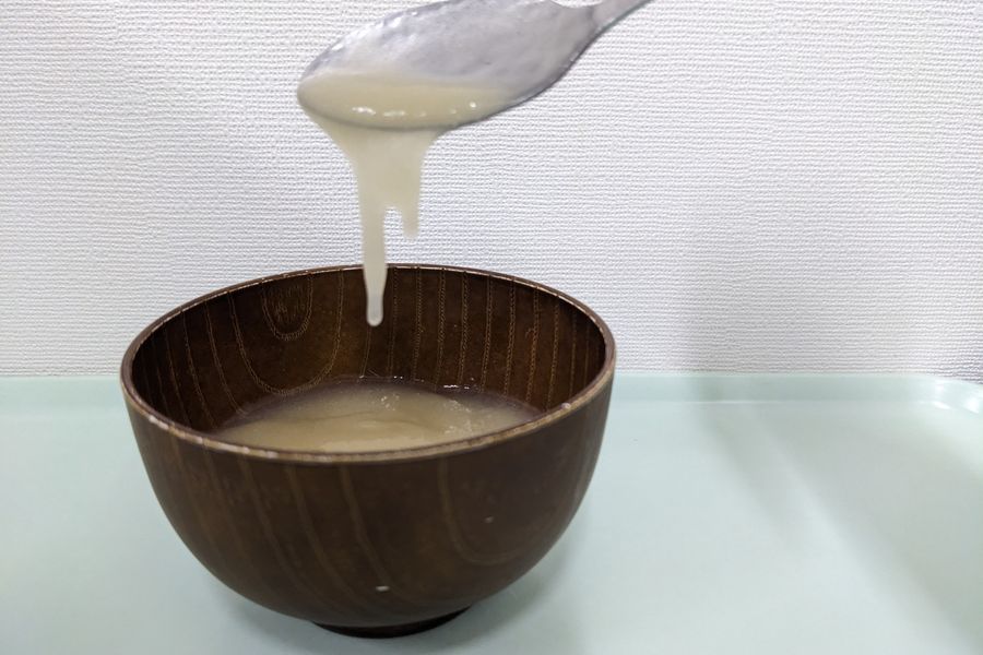 濃いとろみをつけたみそ汁を、スプーンですくったようす。形が保たれ、ゆっくり落ちる