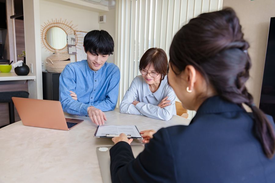 書類を見せながら、高齢の夫婦に契約の内容を説明する女性