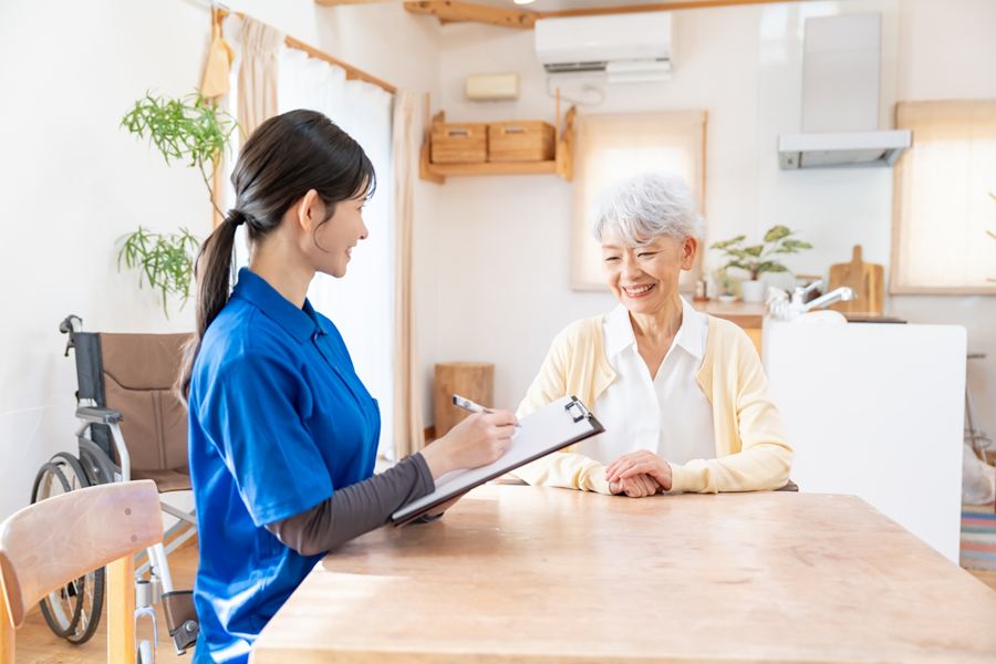 高齢の女性の話を聞きながら、記録をとるスタッフ