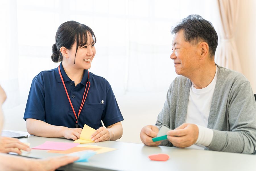 折り紙をしながら話す、介護スタッフと高齢の男性