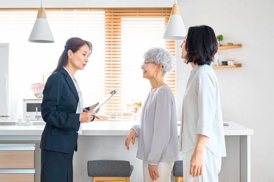 タブレットを手に、高齢の女性と家族に説明するスタッフ
