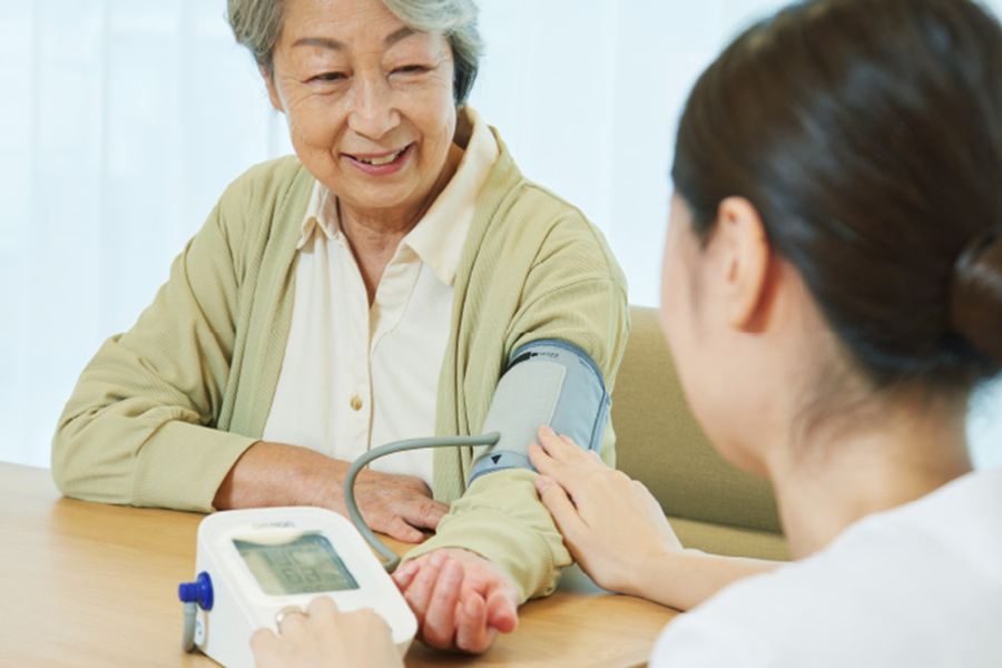 看護師が入居者の血圧を測るようす