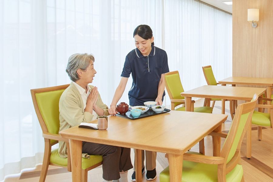 リビングで、入居者に食事を運ぶスタッフ