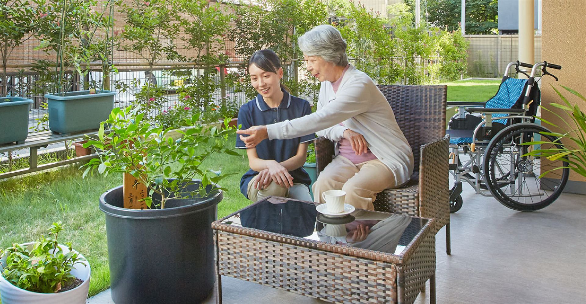 中庭のテラスで入居者とスタッフが植栽を眺めるようす(東急ウェリナケア旗の台)