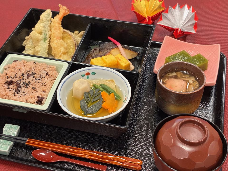 敬老の日の松花堂弁当。天ぷら、煮物、赤飯、吸い物と、折り紙の飾り