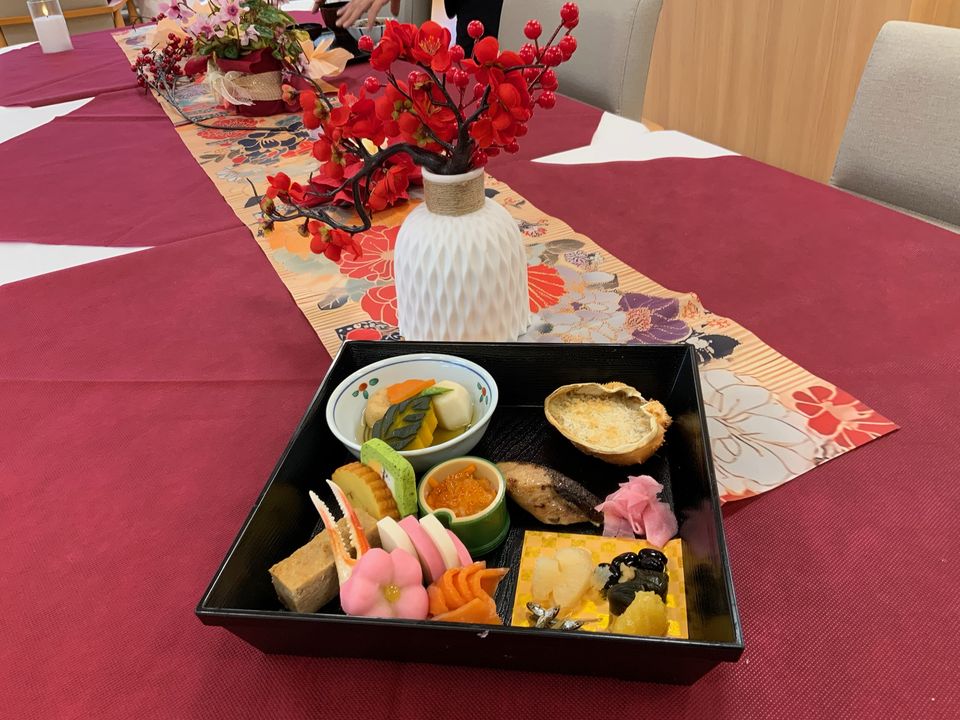 元旦のおせち料理。重箱に盛った料理と、花を飾ったテーブル