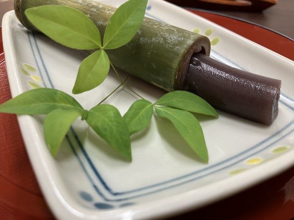 竹筒に入った水ようかんを、葉を添えた器に盛ったおやつ